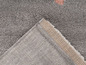 Détail d'un tapis gris avec des accents roses.