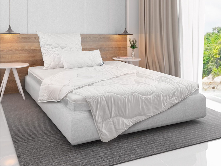 Draps blancs sur un lit avec une tête de lit en bois.