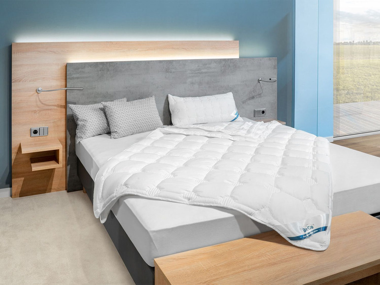 Une couette blanche Beco sur un lit avec des oreillers