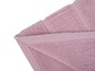 Une serviette de bain rose pliée sur un fond blanc.