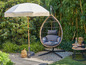 Un fauteuil suspendu et un parasol dans un jardin.