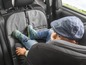 Un enfant dans un siège auto avec une housse de protection pour le siège.