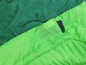 Sac de couchage vert avec une poche pour un téléphone.