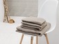 Une pile de serviettes de bain beiges sur une chaise blanche.
