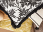 Coussin avec des franges noires et un motif tropical