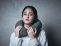 Une femme portant une chemise blanche avec un coussin de cou gris foncé.
