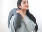 Une femme avec un coussin de voyage Synca gris.