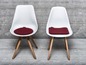 Deux chaises blanches avec des coussins rouges.