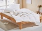 Une couette et des oreillers blancs sur un lit en bois.