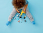 Un enfant joue avec des jouets LEGO DUPLO, dont une pelle mécanique jaune.