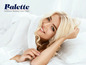 Une femme sourit dans un lit avec des draps Balette.