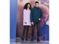 Un homme et une femme portent des imperméables et des bottes de pluie.