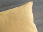 Un coussin jaune sur un sol en bois.