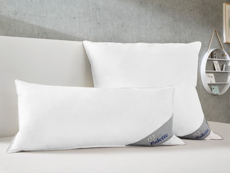 Deux oreillers blancs de la marque Ballett sur un lit blanc.