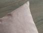 Un coussin rose en tissu à texture tissée grossière.