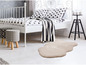Un lit blanc avec une couverture rayée blanc et noir et un tapis beige.