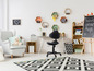 Une chambre d'enfant avec un fauteuil de bureau noir, un fauteuil gris et un tapis noir et blanc.