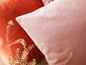 Un coussin rose avec un motif géométrique à côté d'un coussin orange.