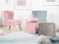 Un fauteuil rose en velours, un pouf gris et un fauteuil bleu dans une chambre d'enfant.