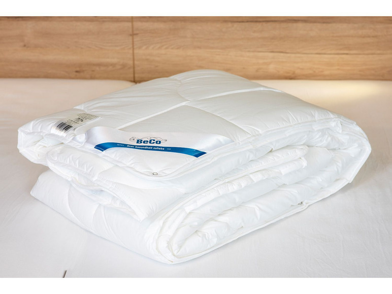 Une couette blanche BeCo pliée sur un lit.
