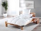 Une couette et un oreiller blancs sur un cadre de lit en bois.
