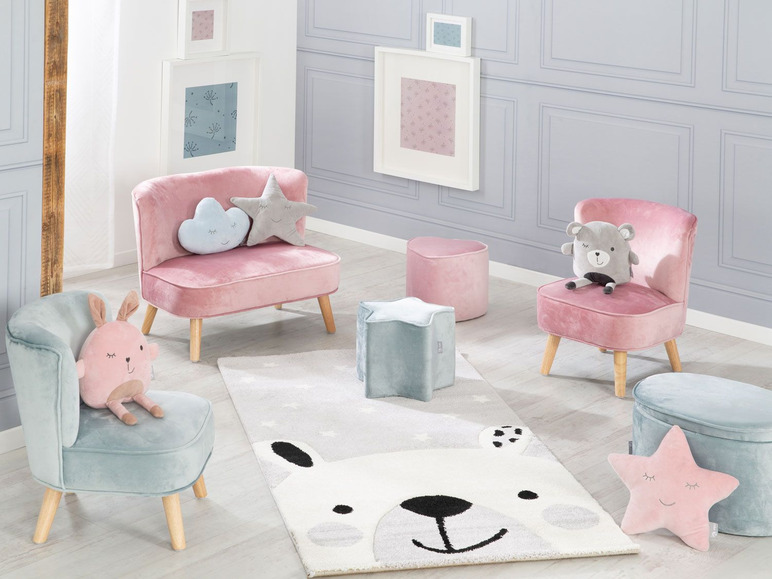 Deux fauteuils en velours rose, un fauteuil bleu et un tapis avec un motif d'ours.