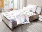 Un lit avec une couette et des oreillers blancs.