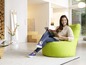 Une femme lit dans un fauteuil beanbag vert.