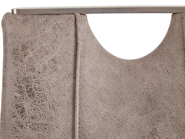Détail d'un dossier de chaise avec un revêtement en cuir gris et une structure métallique.