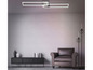 Un luminaire rectangulaire moderne au-dessus d'un fauteuil en cuir dans une pièce avec un mur en briques blanches.