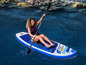 Une femme pagaye sur une planche à pagaie gonflable en mer.
