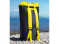 Un sac à dos noir avec des bretelles jaunes sur une plage de galets.