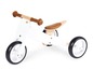 Un vélo d'apprentissage en bois blanc avec des poignées et une selle marrons.