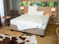 Un lit avec une couette blanche de la marque Bico, deux oreillers et un tapis.