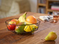 Un panier à fruits noir avec des bananes, un pamplemousse, une mangue, un citron et des pommes.