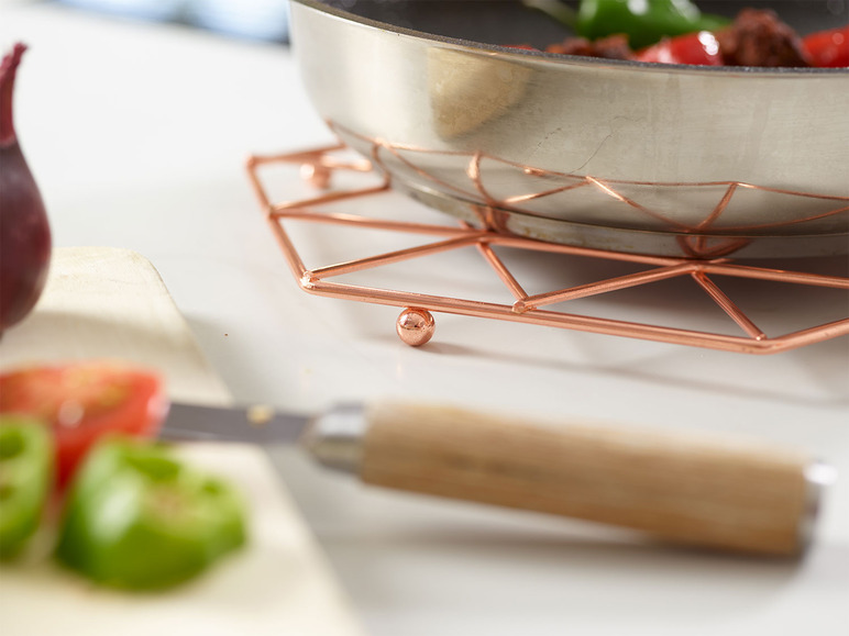 Un dessous de plat en cuivre avec une casserole dessus.