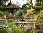 Deux chaises en bambou et une table avec deux bonsaïs LEGO dans un jardin.