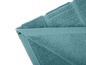 Un tapis de bain bleu plié sur un fond blanc.