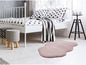 Un tapis en peau de mouton rose sous un lit avec des draps noirs et blancs.