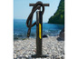 Une pompe à main Hydro-Force noire pour articles de sport nautiques gonflables sur une plage de galets.