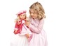 Une fille joue avec une poupée rose portant une robe rose.