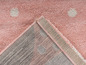 Tapis rose à pois blancs et bord beige.