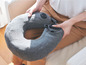 Une femme tenant un coussin de voyage gonflable gris.