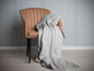 Une couverture en polaire grise sur un fauteuil brun.