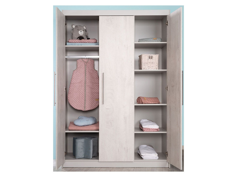 Une armoire avec un sac de couchage pour bébé, des couvertures et des jouets.