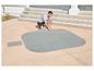 Un homme pose des dalles grises Lay-Z-Spa sur une terrasse.