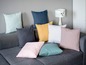 Coussins de différentes couleurs sur un canapé gris.