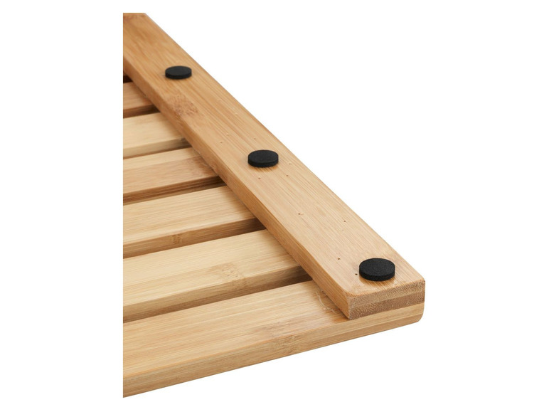 Un tapis de bain en bois avec des pieds antidérapants.
