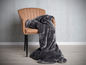 Une couverture en fourrure grise sur un fauteuil en cuir marron.