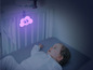 Un bébé dans un berceau avec une veilleuse en forme de nuage.